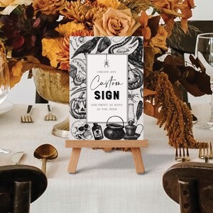 May include: A custom sign on a small wooden easel, featuring Halloween-themed illustrations like pumpkins, skulls, and a crow. The sign reads "Create Any Custom Sign and Print as Many as You Need."