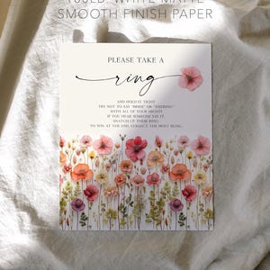 K&ouml;nnte beinhalten: Wei&szlig;es, mattes Papier mit floralem Design und dem Text "Please take a ring". Der untere Teil der Karte zeigt einen Aquarell-Blumenrand mit rosa, orangefarbenen und lila Blumen. Der Text enth&auml;lt auch den Satz "Creative Union Design."