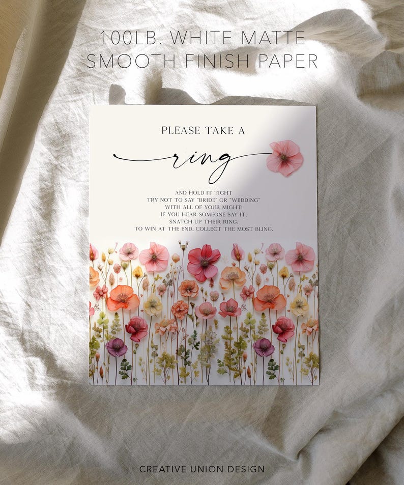 K&ouml;nnte beinhalten: Wei&szlig;es, mattes Papier mit floralem Design und dem Text "Please take a ring". Der untere Teil der Karte zeigt einen Aquarell-Blumenrand mit rosa, orangefarbenen und lila Blumen. Der Text enth&auml;lt auch den Satz "Creative Union Design."