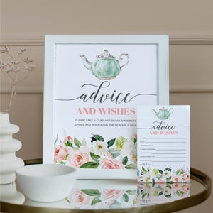 Può includere: Un cartello incorniciato e una carta abbinata con le parole "advice and wishes". Il cartello presenta una teiera ad acquerello e un design floreale in rosa e verde. La carta ha richieste da compilare. Il cartello è in una cornice bianca.