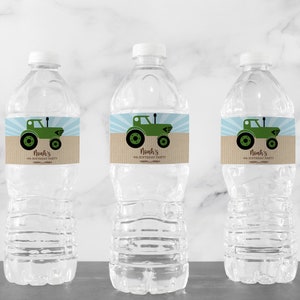 May include: Three clear plastic water bottles with white caps. Each bottle has a label featuring a green tractor illustration on a tan background with blue rays. The text on the label reads "Noah's 4th Birthday Party".