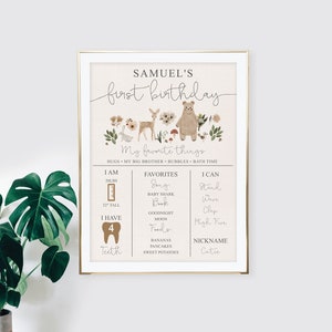 May include: A printable first birthday chart for a boy named Samuel. The chart features a woodland theme with a brown bear, deer, and other forest animals. It includes details about the child's age, weight, height, favorite things, and skills. The chart is decorated with a floral border.