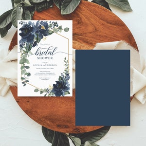 Op de afbeelding: Een uitnodiging voor een bruidsdouche met marineblauwe bloemaccenten en een gouden geometrische lijst. De uitnodiging bevat de tekst "bridal shower" en evenementdetails. Een bijpassende marineblauwe kaart is ook aanwezig.