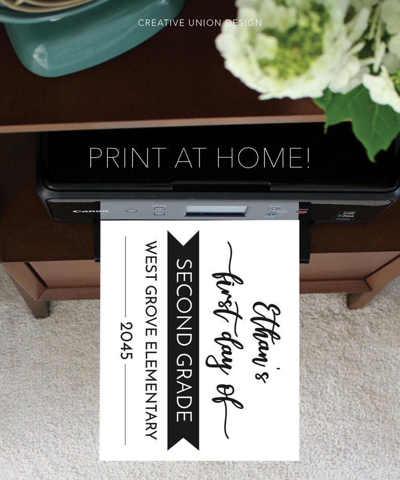 May include: A black Canon printer outputting a white sheet of paper with black text that reads: Ethan's first day of SECOND GRADE WEST GROVE ELEMENTARY 2045. The text PRINT AT HOME is visible above the printer, and the brand name Creative Union Design appears.
