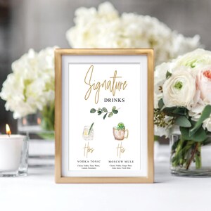 Puede incluir: Un cartel con marco dorado con el texto "Signature Drinks" e ilustraciones de dos c&oacute;cteles. El texto "Hers" est&aacute; sobre un vaso de vodka tonic con una rodaja de lim&oacute;n y una ramita de romero. El texto "His" est&aacute; sobre una taza de cobre con un Moscow mule con una rodaja de lima y una ramita de menta. El texto debajo de las ilustraciones describe los ingredientes de cada bebida.