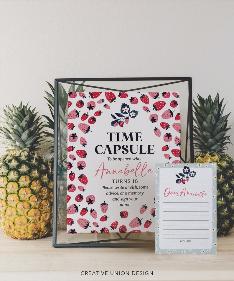 May include: A white card with a strawberry pattern and the text "Time Capsule" and "To be opened when Annabelle turns 18".  The card also includes instructions to write a wish, some advice, or a memory and sign your name.  A blue card with white flowers and the text "Dear Annabelle" is next to the white card.