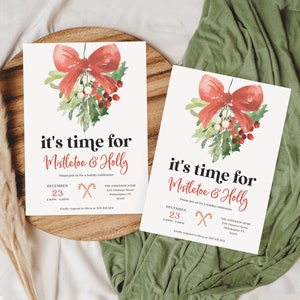 Op de afbeelding: Twee kerstuitnodigingskaarten met een aquarelontwerp van een rode strik, maretak en hulst. De tekst luidt "it's time for Mistletoe & Holly" met evenementdetails. De kaarten liggen op een houten dienblad met een groene stoffen achtergrond.