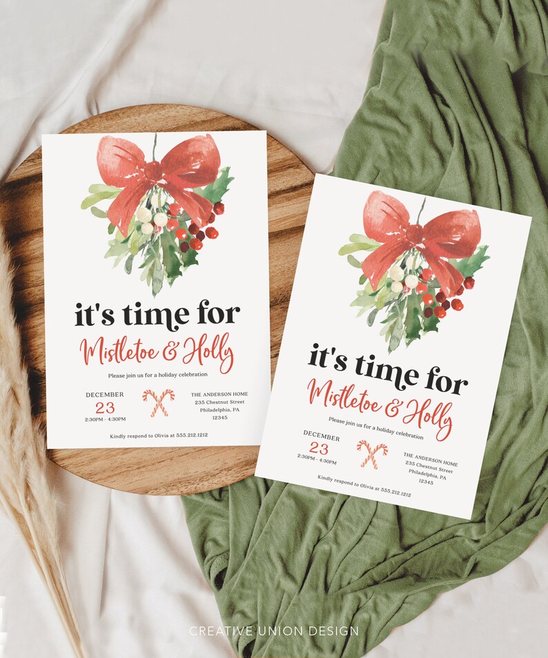 Op de afbeelding: Twee kerstuitnodigingskaarten met een aquarelontwerp van een rode strik, maretak en hulst. De tekst luidt "it's time for Mistletoe & Holly" met evenementdetails. De kaarten liggen op een houten dienblad met een groene stoffen achtergrond.