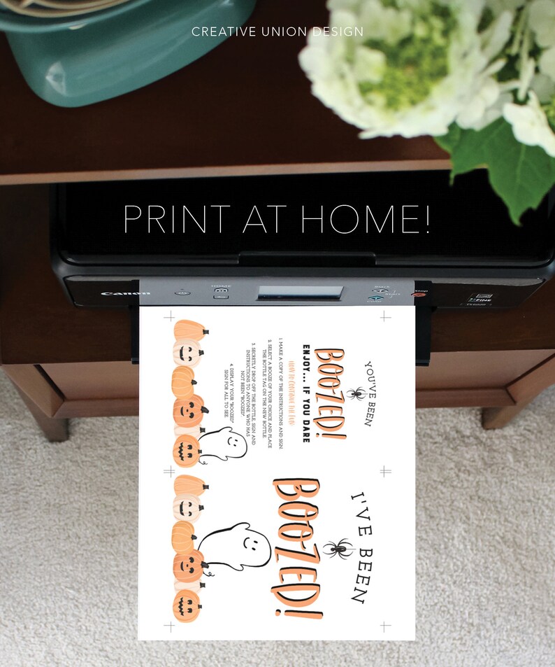 K&ouml;nnte beinhalten: Ein Drucker druckt ein Design zum Thema Halloween. Das gedruckte Blatt zeigt den Text "Boozed!" mit Geister- und K&uuml;rbisgrafiken. Die Worte "Print at Home!" werden &uuml;ber dem Drucker angezeigt.