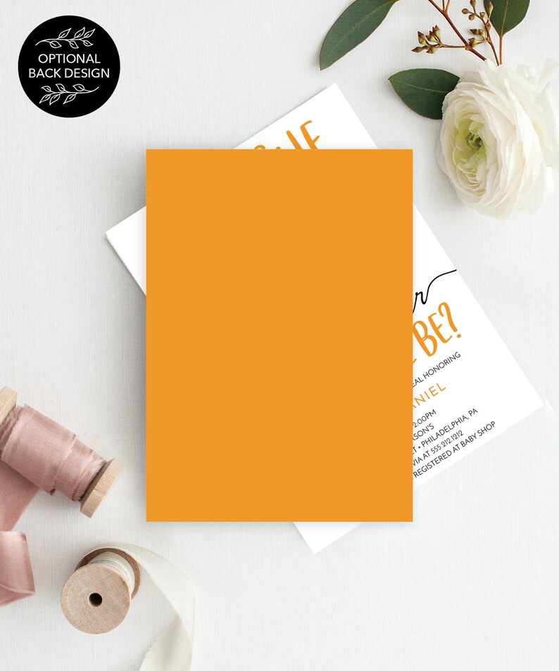 May include: A white card with black text that reads "Q  r BE?"  The card is on a white background with a yellow card and a white flower. The text on the card also reads "A Baby Shower Honoring [Name] 2:00PM [Location] [Address] Registered at Baby Shop"