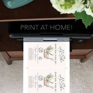 May include: A black Canon printer outputting two identical gender reveal invitation cards. Each card features a watercolor illustration of a wicker baby carriage with greenery, the text "He or She", "WHAT WILL BABY BE?", and event details.