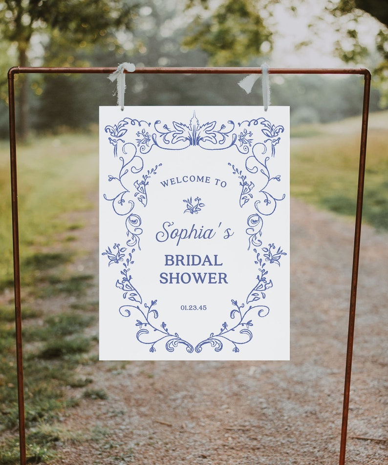 May include: White sign with blue floral border and text that reads "Welcome to Sophia's Bridal Shower 01.23.45".