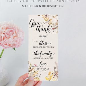 May include: A rectangular card with the words "Give thanks" in elegant script, surrounded by floral accents. The card includes the text "bless the food before us, the family beside us, and the love between us, amen."