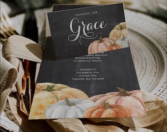 Puede incluir: Una tarjeta de menú con un fondo de estilo pizarra con calabazas de acuarela en tonos naranja, blanco y melocotón. El texto "THANKFUL FOR Grace" se muestra en una elegante escritura. El menú enumera guarniciones y postres, incluyendo pastel de calabaza y pastel de nuez pecana.