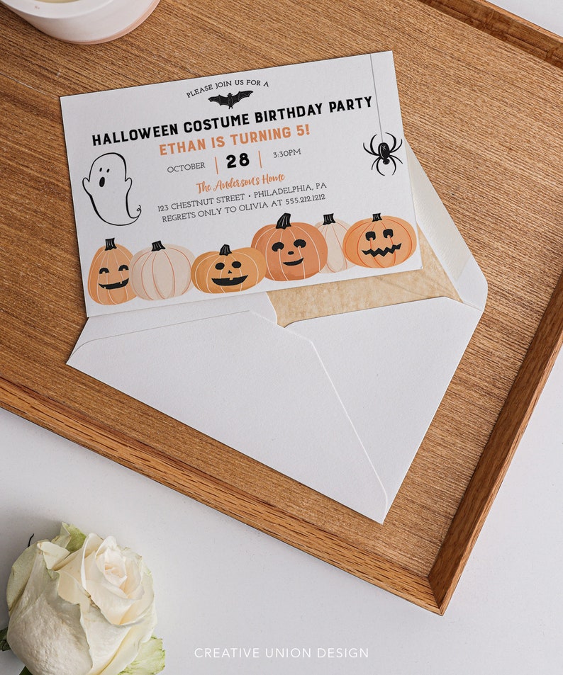 以下が含まれることがあります： 「HALLOWEEN COSTUME BIRTHDAY PARTY」と「ETHAN IS TURNING 5！」の文字が入った、ハロウィーンをテーマにした誕生日パーティーの招待状。カボチャ、幽霊、コウモリ、クモのイラストが特徴です。招待状は白い封筒の中に入っています。