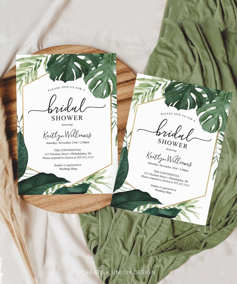 May include: Two white invitation cards with gold trim and green tropical leaf designs. The text on the cards reads "Please join us for a bridal shower honoring Kaitlyn Williams. Saturday, November 23rd, 2:00pm. The Continental, 123 Chestnut Street, Philadelphia, PA. Please respond to Jessica at 555.212.1212. Sophia is registered at Wedding Shop."