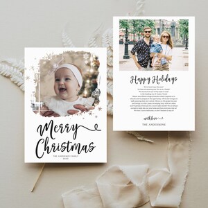 May include: A set of two holiday cards. One card features a baby's photo with "Merry Christmas" in elegant script. The other card has a family photo with "Happy Holidays" and a personal message. Both cards have a white background.