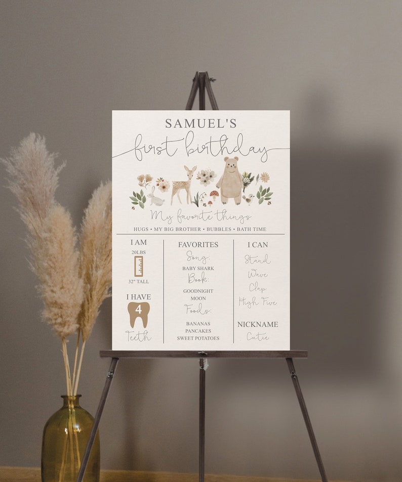 May include: A beige and brown illustrated poster with a woodland theme. The poster says "Samuel's first birthday" and includes details about the child's age, height, favorite things, and abilities. The poster features a cute illustration of a bear, deer, and rabbit.