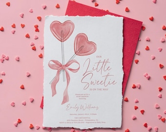 May include: Pink baby shower invitation featuring a watercolour illustration of two pink heart-shaped lollipops tied with a pink ribbon. The text reads "Our Little Sweetie is on the way".