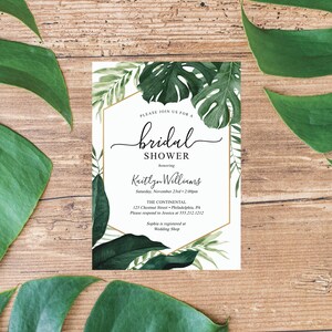 May include: A white bridal shower invitation with a gold border and tropical leaf illustrations. The invitation reads "Please join us for a bridal shower honoring Kaitlyn Williams, Saturday, November 23rd, 2:00pm, The Continental, 123 Chestnut Street, Philadelphia, PA, Please respond to Jessica at 555.212.1212, Sophia is registered at Wedding Shop."