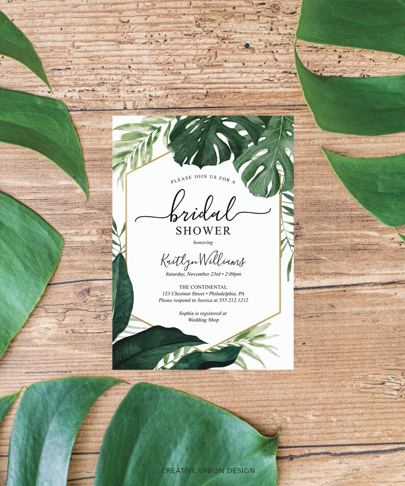 May include: A white bridal shower invitation with a gold border and tropical leaf illustrations. The invitation reads "Please join us for a bridal shower honoring Kaitlyn Williams, Saturday, November 23rd, 2:00pm, The Continental, 123 Chestnut Street, Philadelphia, PA, Please respond to Jessica at 555.212.1212, Sophia is registered at Wedding Shop."
