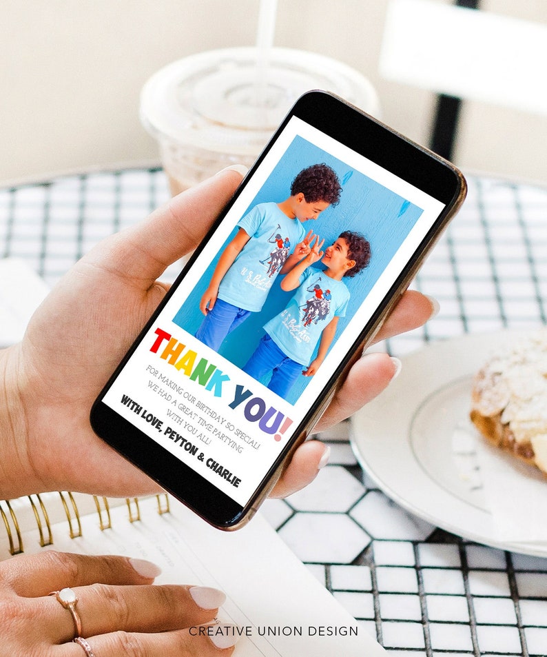 May include: A smartphone displays a digital card with the words "THANK YOU!" in rainbow colors. The card features a photo of two boys in blue shirts and pants. Text below reads "FOR MAKING OUR BIRTHDAY SO SPECIAL!" and "WITH LOVE, PEYTON & CHARLIE."