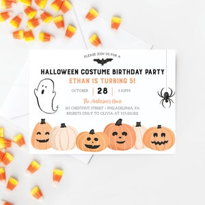 以下が含まれることがあります： 「HALLOWEEN COSTUME BIRTHDAY PARTY」と「ETHAN IS TURNING 5！」のテキストが入ったハロウィーンをテーマにした誕生日パーティーの招待状。 招待状には、幽霊、カボチャ、コウモリ、クモが描かれています。 散らばったキャンディーコーンがあります。