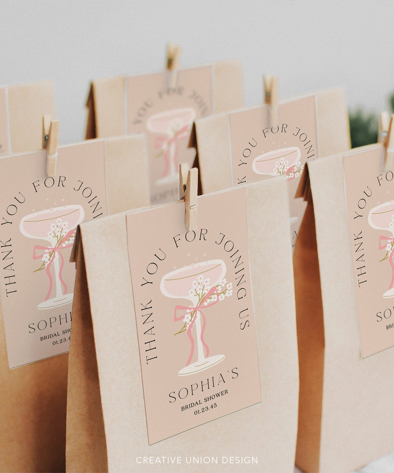 Op de afbeelding: Dank je voor je komst bruiloft douche cadeauzakjes met een roze champagne glas ontwerp en de tekst "Bedankt voor je komst Sophia's Bridal Shower 01.23.45"