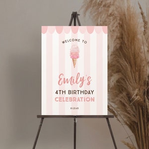 May include: A pink and white striped welcome sign for a birthday celebration. The sign reads "Welcome to Emily's 4th Birthday Celebration" with an ice cream cone graphic. The sign is displayed on a wooden easel.