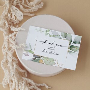May include: A white thank you card with green watercolor leaves and gold accents. The text reads "Thank you from the future Mrs. Anderson".