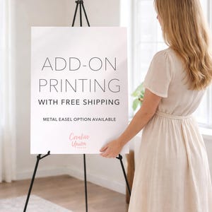 May include: A white sign on a black metal easel with the text "ADD-ON PRINTING" and "METAL EASEL OPTION AVAILABLE". The sign is held by a person wearing a light-colored dress.