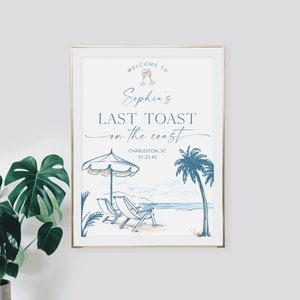 May include: A white sign with blue text and illustrations announcing "Welcome to Sophia's Last Toast on the Coast" with the location Charleston, SC and a date. The sign features a beach scene with palm trees, beach chairs, and an umbrella.