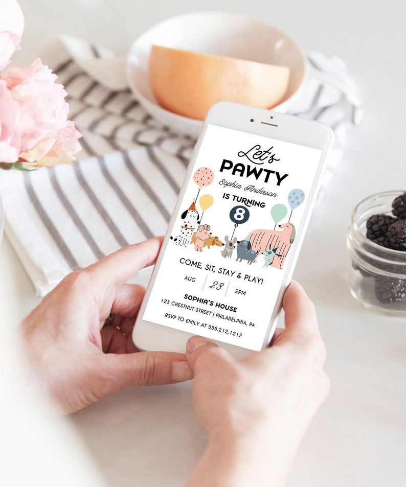 May include: A smartphone displaying a colorful invitation for a dog-themed birthday party. The invitation reads "Let's Pawty" and features a cartoon illustration of dogs with balloons. The text includes the birthday girl's name, age, date, time, and location.