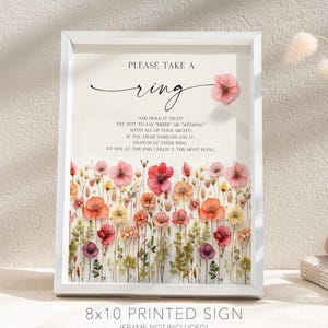K&ouml;nnte beinhalten: Ein gerahmtes, bedrucktes Schild im Format 20x25 cm mit floralem Design. Auf dem Schild steht "Please Take a Ring" mit Anweisungen f&uuml;r ein Hochzeitsspiel. Der untere Teil des Schildes tr&auml;gt den Text "Creative Union Design".