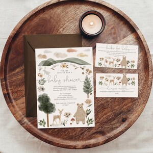 Peut inclure: Une invitation de f&ecirc;te pr&eacute;natale sur le th&egrave;me de la for&ecirc;t avec une illustration aquarelle d'un ours, d'un cerf et d'une for&ecirc;t. L'invitation comprend le texte "Veuillez vous joindre &agrave; nous pour une f&ecirc;te pr&eacute;natale" et les d&eacute;tails de l'&eacute;v&eacute;nement. Il y a aussi deux cartes pour "livres pour b&eacute;b&eacute;" et "tombola de couches".