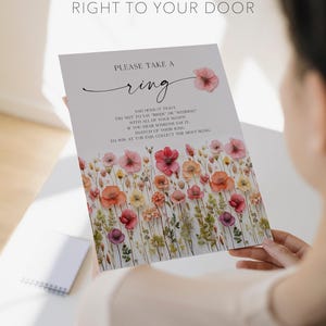 K&ouml;nnte beinhalten: Eine Hochzeitsspielkarte mit floralen Illustrationen und dem Text "PLEASE TAKE A ring". Die Karte enth&auml;lt Anweisungen und ein Aquarell-Blumenmuster in Rosa, Orange und Gelb. Der Text "PRINTED & SHIPPED RIGHT TO YOUR DOOR" steht oben.