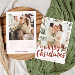 May include: Two Christmas cards with family photos. One card says "Merry Christmas" in red script with a decorative border. The other card has a family photo and text. Both cards are on a wooden tray.