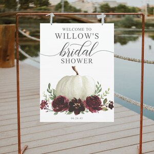 May include: White pumpkin with burgundy floral accents and greenery. Text reads "Welcome to Willow's bridal shower 06.26.45".
