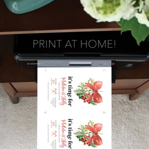 Op de afbeelding: Een printer drukt twee uitnodigingen af. De uitnodigingen hebben een aquarelontwerp met een rode strik, hulst en bessen. De tekst op de uitnodigingen luidt "it's time for Mistletoe & Holly" en "Print at Home!"