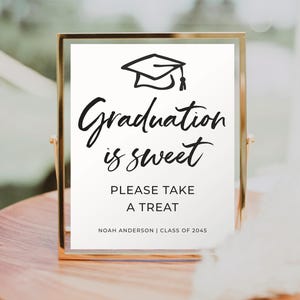 Könnte beinhalten: Ein goldfarbener Rahmen mit einem weißen Hintergrund und schwarzem Text, der "Graduation is sweet. Please take a treat. Noah Anderson | Class of 2045" lautet. Oberhalb des Textes befindet sich eine Schwarzweißillustration einer Graduation Cap.