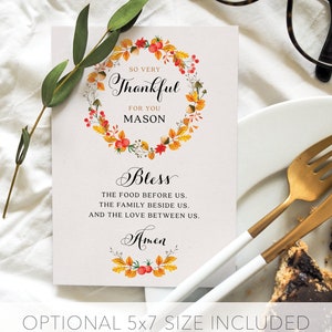May include: A Thanksgiving place card with a watercolor wreath of fall leaves and berries. The card says "So very thankful for you Mason" and "Bless the food before us, the family beside us, and the love between us. Amen".