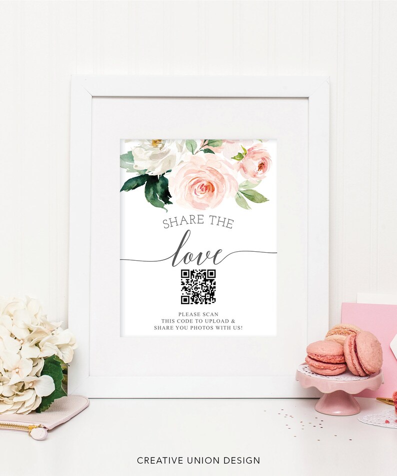 K&ouml;nnte beinhalten: Wei&szlig; gerahmtes Schild mit floralen Akzenten und dem Text "SHARE THE love". Enth&auml;lt einen QR-Code und den Text "PLEASE SCAN THIS CODE TO UPLOAD & SHARE YOU PHOTOS WITH US!". Das Schild ist mit rosa Rosen und wei&szlig;en Blumen verziert.