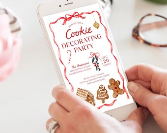 May include: A white smartphone displays a Christmas-themed invitation for a cookie decorating party. The invitation features red ribbon accents, festive illustrations, and the text "Cookie Decorating Party."
