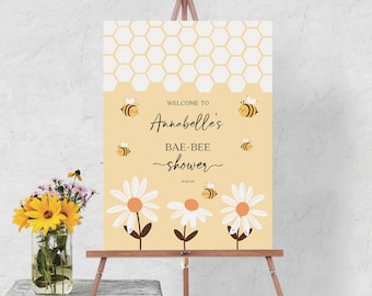 Könnte beinhalten: Ein gelbes und weißes Willkommenszeichen mit einem Wabenmuster und Comic-Bienen. Das Schild lautet "Willkommen zu Annabelles Bae-Bee Shower 02.23.43".
