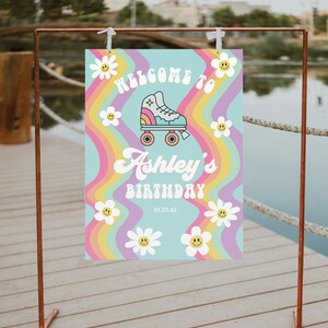 K&ouml;nnte beinhalten: Willkommen zum Geburtstag von Ashley Schild mit Regenbogenhintergrund und einem Rollschuh-Motiv. Das Schild hat einen blauen Hintergrund mit wei&szlig;en G&auml;nsebl&uuml;mchen und einem gelben Smiley.