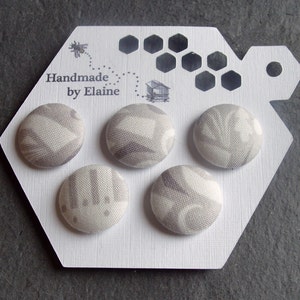May include: Five round fabric-covered buttons with a grey and white pattern, displayed on a white hexagonal card. The card has a bee illustration and the text "Handmade by Elaine". The buttons are approximately 2.5 cm in diameter.