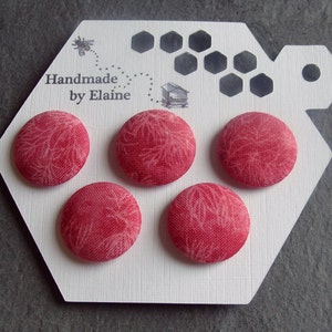 May include: Set of four red fabric buttons with a white floral pattern. The buttons are displayed on a white hexagonal card with the text "Handmade by Elaine".
