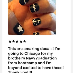 May include: Black nail decals featuring white graphic designs including a five-pointed star, a nautical anchor, and a zigzag pattern. These adhesive nail art stickers are applied to the fingernails, showcasing a high-contrast monochrome aesthetic.