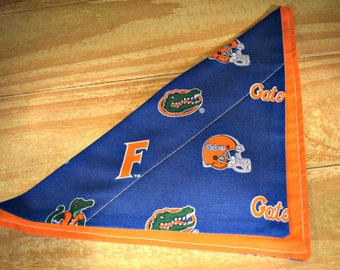 May include: A blue and orange bandana with the University of Florida Gators logo and the letter "F" in the center. The bandana has an orange border.