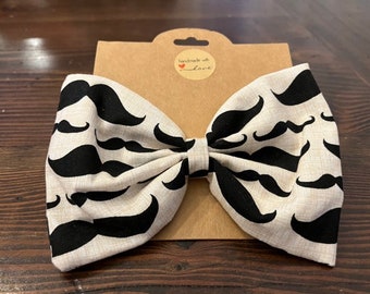 May include: A white bow tie with a black mustache pattern. The bow tie is handmade with love.